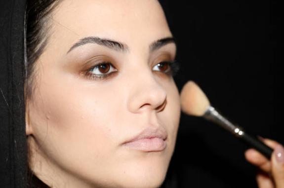 Applying light powder with a fluffy brush to make makeup last longer